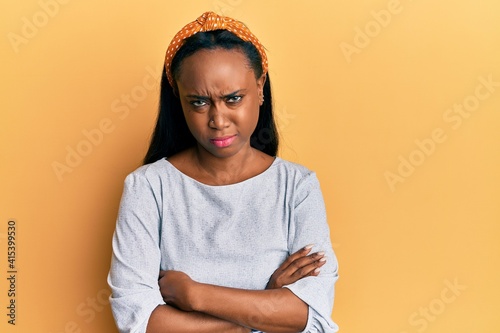 Young african woman wearing casual clothes over yellow background skeptic and nervous  disapproving expression on face with crossed arms. negative person.
