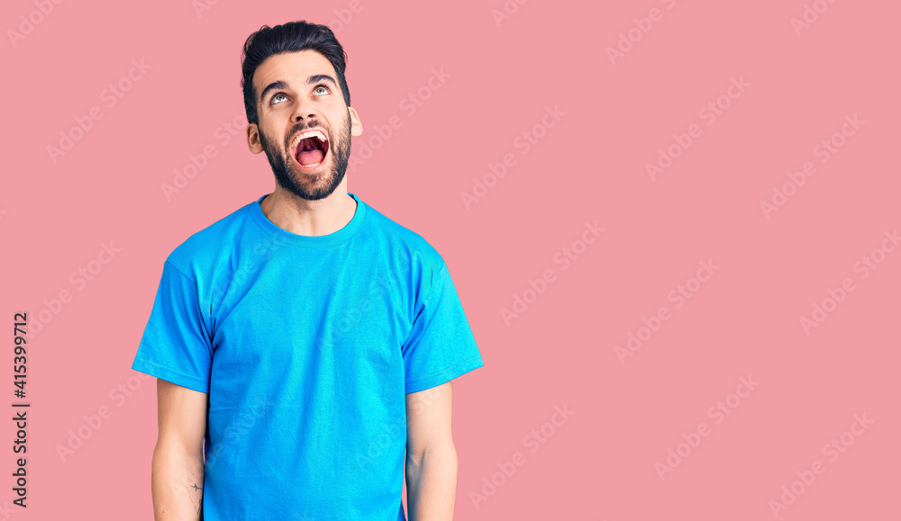 Young handsome man with beard wearing casual t-shirt angry and mad screaming frustrated and furious, shouting with anger. rage and aggressive concept. Young handsome man with beard wearing casual t-shirt angry and mad screaming frustrated and furious, shouting with anger. rage and aggressive concept.