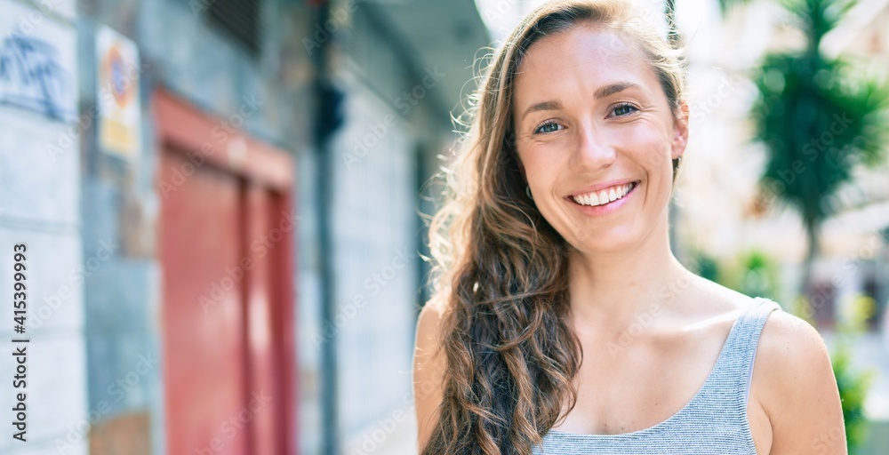 Young blonde woman smiling happy walking at street of city