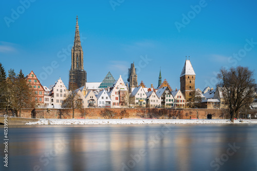 City Ulm with river danube in winter at sunrise with blue sky and snow. Ulmer minster and tower metzgerturm. Panorama long exposure. Travel, vacation