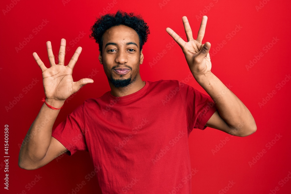 Young african american man with beard wearing casual red t shirt showing and pointing up with fingers number eight while smiling confident and happy. Young african american man with beard wearing casual red t shirt showing and pointing up with fingers number eight while smiling confident and happy.