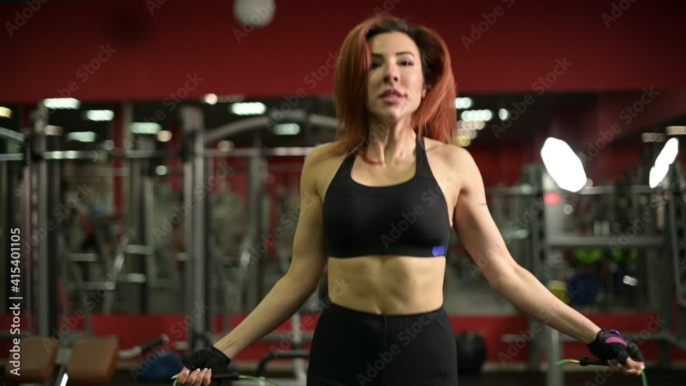 Young woman warming up before training in the gym, jumping rope, close up Young woman warming up before training in the gym, jumping rope, close up