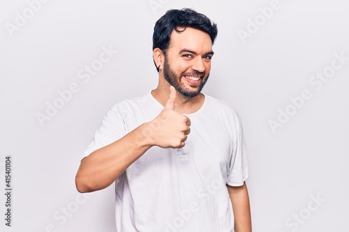 Young hispanic man wearing casual clothes doing happy thumbs up gesture with hand. approving expression looking at the camera showing success.