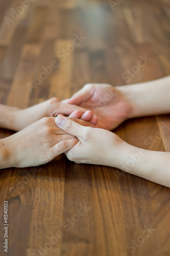 Cropped shot of a young couple holding hands on a wooden table