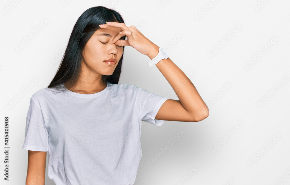 Beautiful young asian woman wearing casual white t shirt tired rubbing nose and eyes feeling fatigue and headache. stress and frustration concept. Beautiful young asian woman wearing casual white t shirt tired rubbing nose and eyes feeling fatigue and headache. stress and frustration concept.