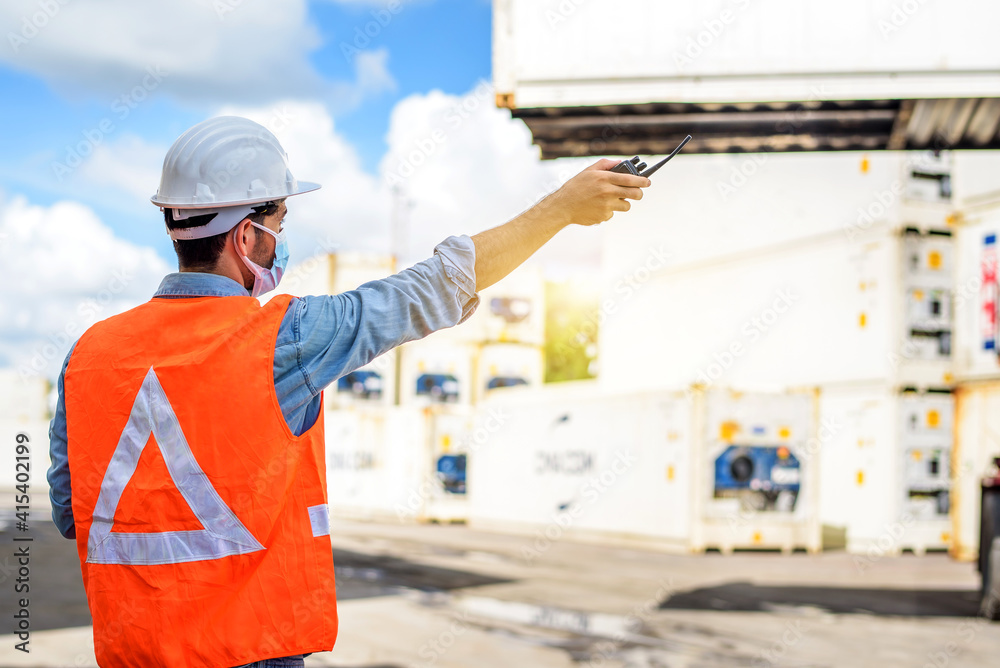Young confident Caucasian man engineer standing with box container background and check for control loading containers box from Cargo freight ship for import and export, transport Young confident Caucasian man engineer standing with box container background and check for control loading containers box from Cargo freight ship for import and export, transport