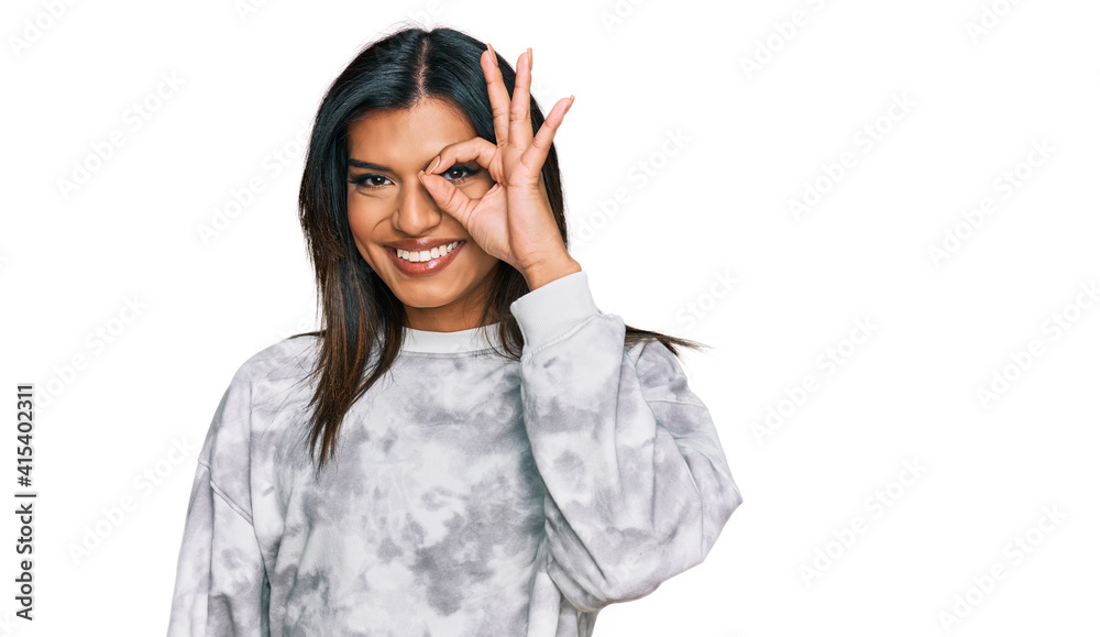 Young latin transsexual transgender woman wearing casual clothes doing ok gesture with hand smiling, eye looking through fingers with happy face. Young latin transsexual transgender woman wearing casual clothes doing ok gesture with hand smiling, eye looking through fingers with happy face.