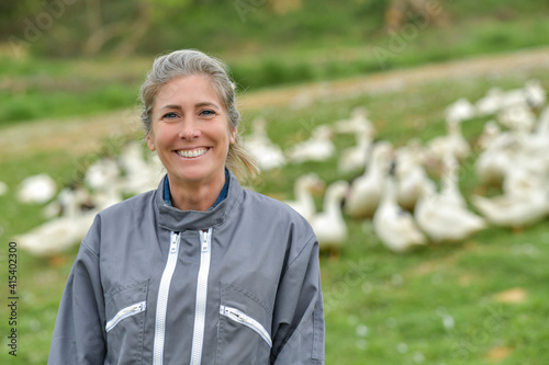 Portrait of a woman standing in the middle of her duck farm in a field