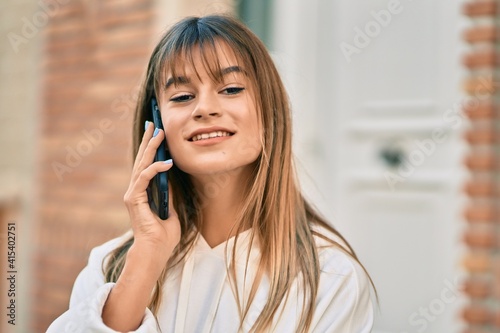 Caucasian sporty teenager girl smiling happy talking on the smartphone at the city.