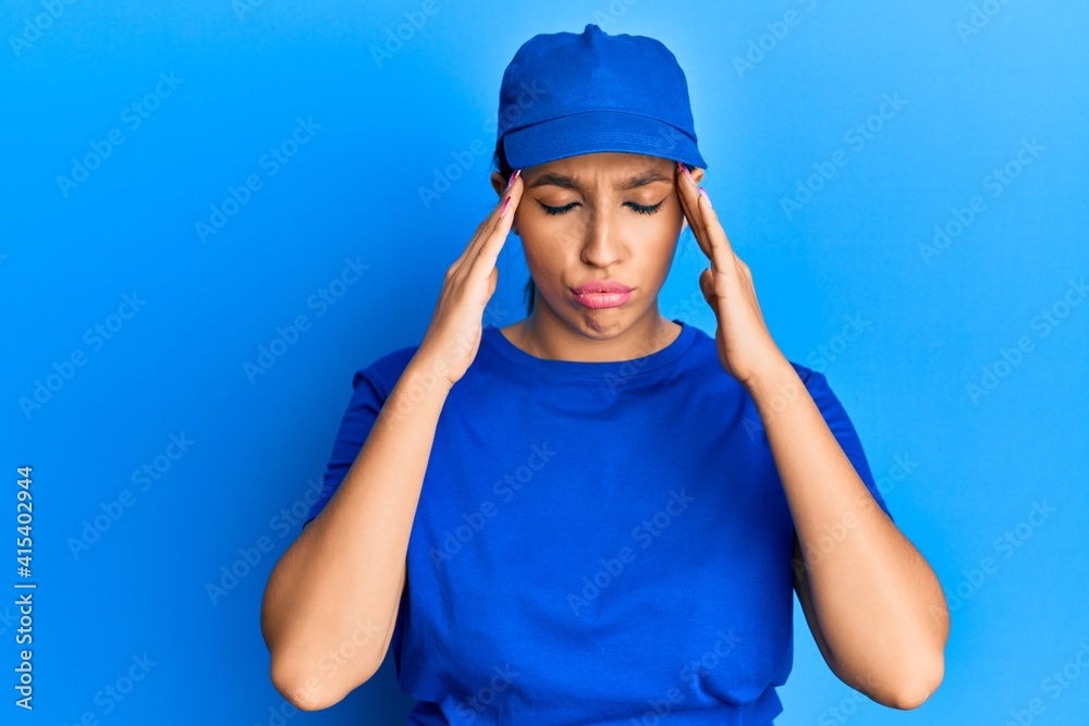 Beautiful brunette woman wearing delivery uniform suffering from headache desperate and stressed because pain and migraine. hands on head. Beautiful brunette woman wearing delivery uniform suffering from headache desperate and stressed because pain and migraine. hands on head.
