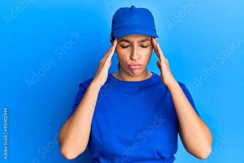 Beautiful brunette woman wearing delivery uniform suffering from headache desperate and stressed because pain and migraine. hands on head.