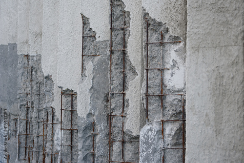 Fotografie Damaged concrete walls with exposed steel reinforcements inside.
