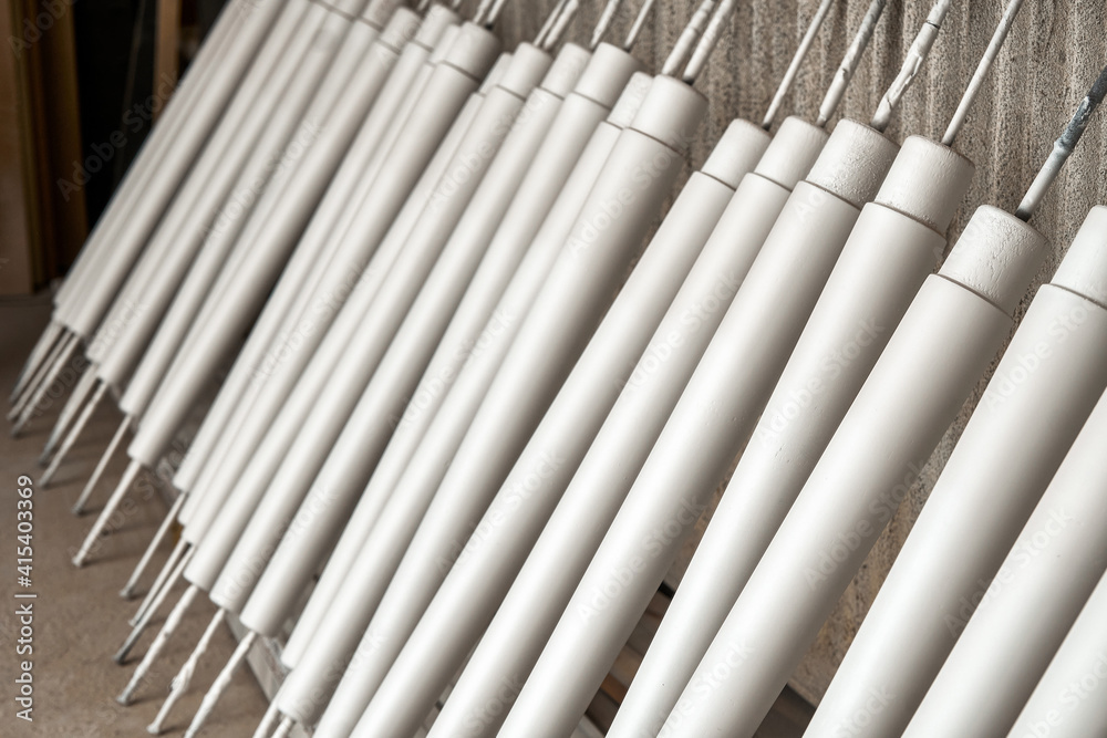 Collection of new wooden furniture legs drying after applying paint leaned on large rack in light woodwork shop extreme close view Collection of new wooden furniture legs drying after applying paint leaned on large rack in light woodwork shop extreme close view