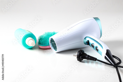 Essential accessories for hair care  and styling, Ionic hairdryer , desired brush and styling spray, in pink mint tone on white background. Modern hairstyling concept.