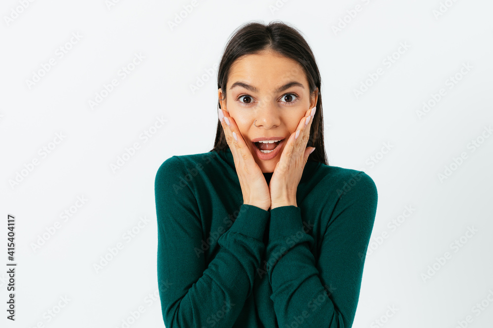 Surprised shocked happy young woman holding palms on her cheeks Surprised shocked happy young woman holding palms on her cheeks