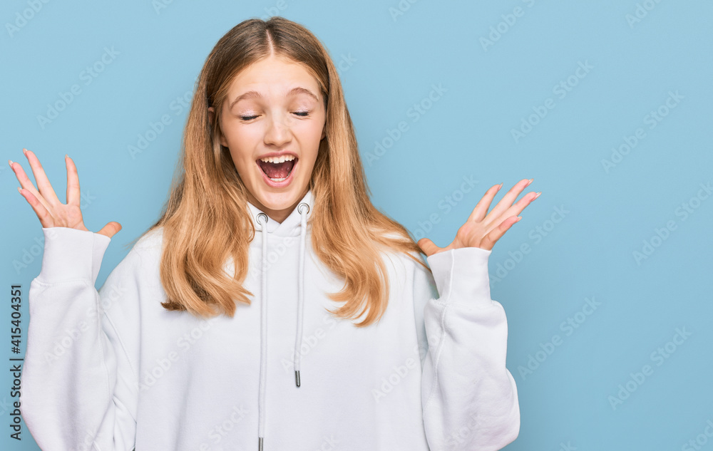 Beautiful young caucasian girl wearing casual sweatshirt celebrating mad and crazy for success with arms raised and closed eyes screaming excited. winner concept Beautiful young caucasian girl wearing casual sweatshirt celebrating mad and crazy for success with arms raised and closed eyes screaming excited. winner concept