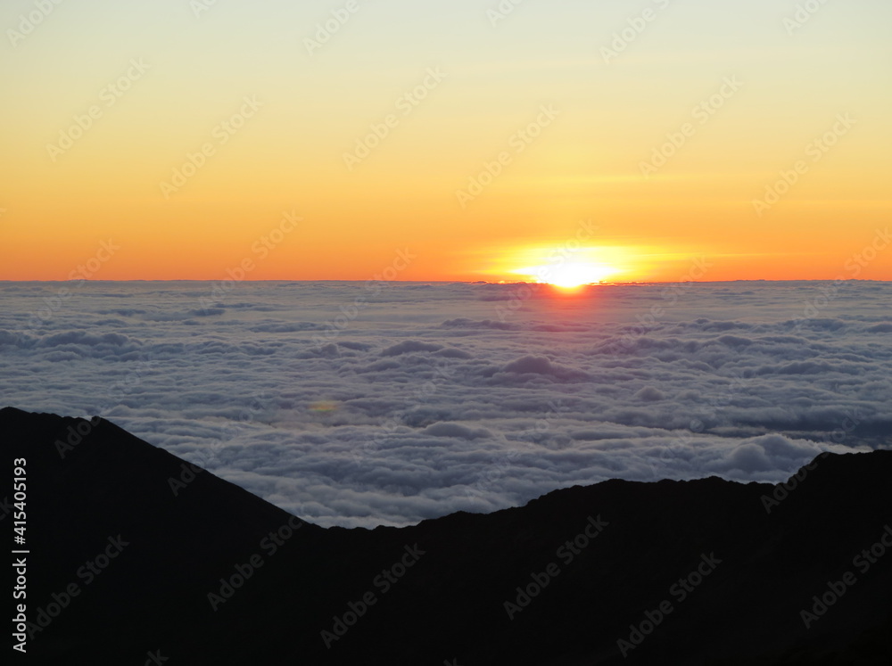 a sunrise over the clouds at the Haleakala volcano on Maui island, Hawaii, January