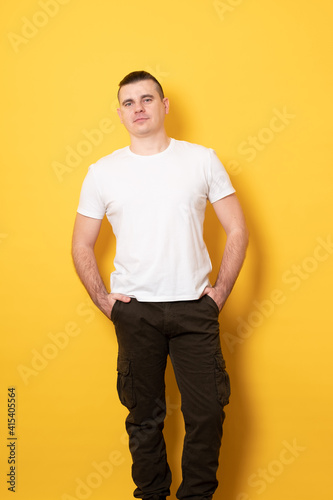 Pensive young man holds his hands in his pants pockets.