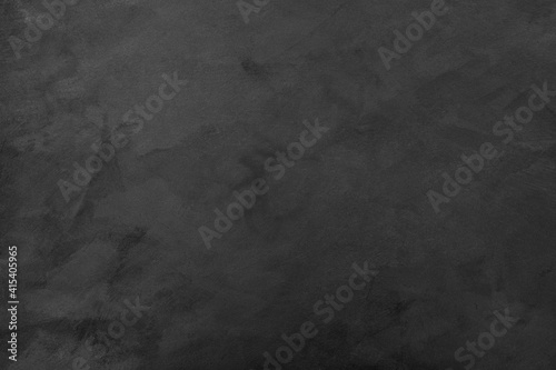 Black textured background made of rough aged plaster with space for text