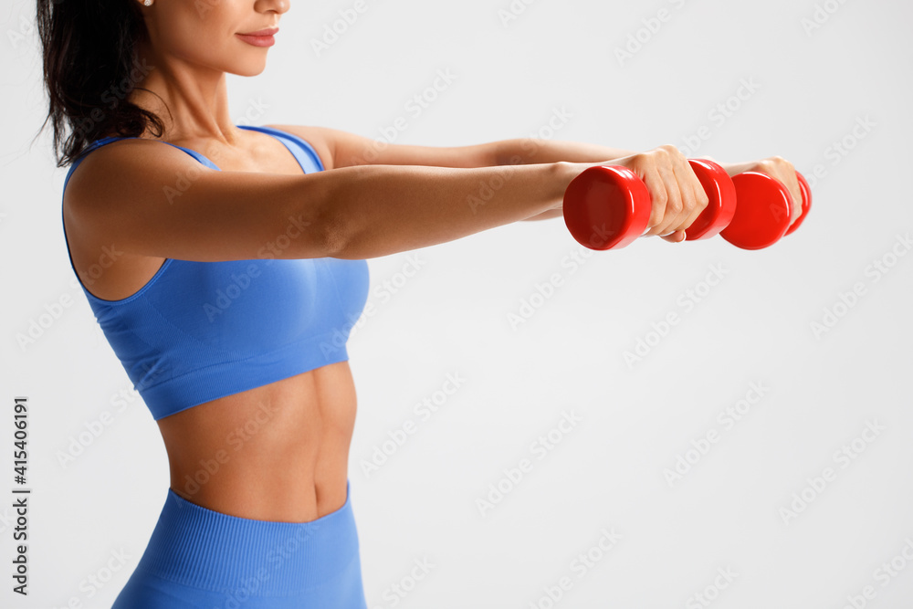 Fitness woman doing exercise with dumbbells on gray background. Athletic girl working out Fitness woman doing exercise with dumbbells on gray background. Athletic girl working out