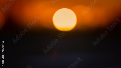 orange disc of the setting sun  blurred background.