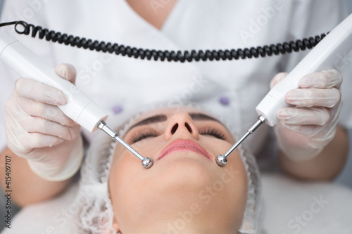 Macro close up portrait of woman having cosmetic galvanic beauty treatment in spa.Therapist applying low frequency current with electrodes on face