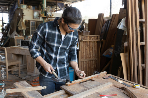 male carpenter using hammer and chisel on a piece of wood in workshop