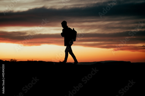 Fototapeta Naklejka Na Ścianę i Meble -  Silhouette male adventurer hiking during sunset on mountain top