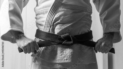 Obraz na plátně Martial artist tightening knot on black belt