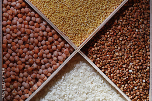 A set of grain cereals. Rice, buckwheat and millet groats in a wooden tray. A grocery set of cereals. Import of grain.