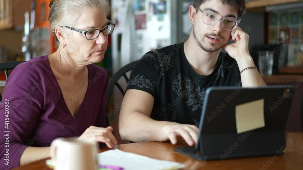 Closeup of home school education parent teaching son at home. Social distancing and self isolation in quarantine lockdown. A Young woman mother teaches her son and works with him on a laptop at home.