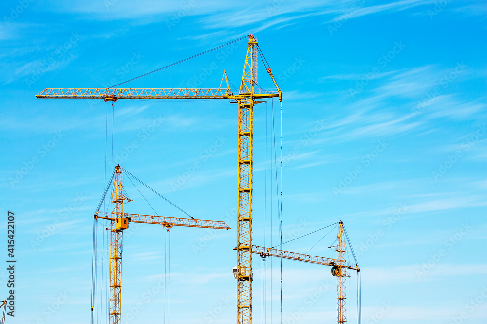 Construction cranes against the blue sky. Construction Construction cranes against the blue sky. Construction