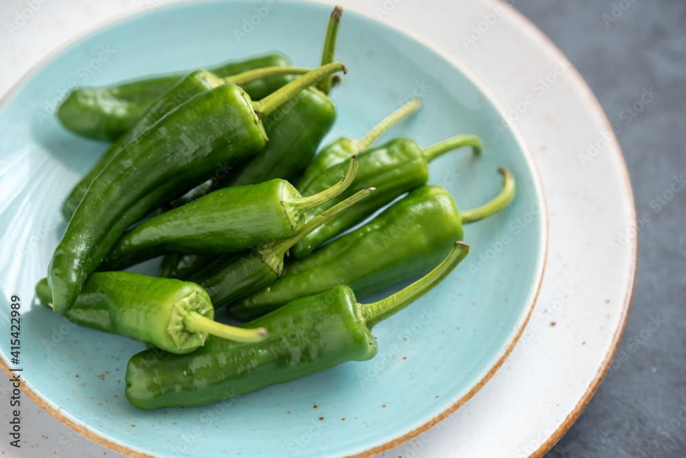 Group of green fresh chilli peppers padron on a plate Group of green fresh chilli peppers padron on a plate
