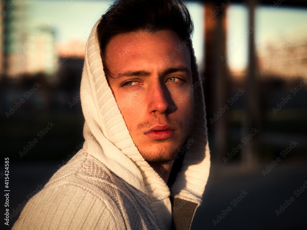 Handsome young man in black hoodie sweater standing outdoor in street Handsome young man in black hoodie sweater standing outdoor in street