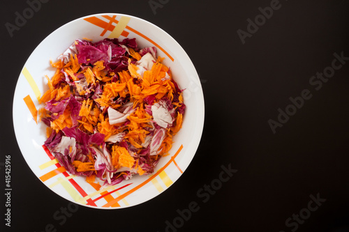 Salad with carrots on black table, top view