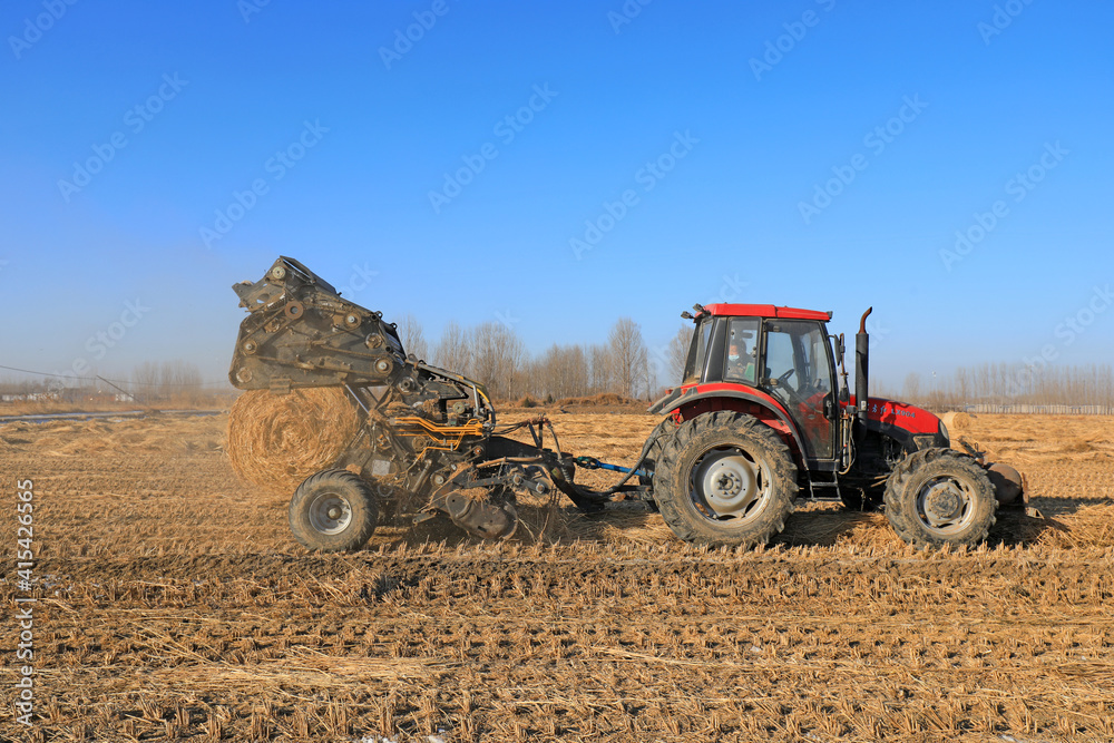 Obraz premium farmers use agricultural machinery to compress rice straw and bundle them on a farm, LUANNAN COUNTY, Hebei Province, China