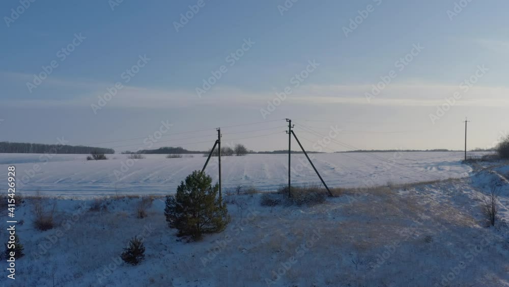 the electrical network is laid along the winter field. electric to remote settlements. wired electrical, span between pillars - Aerial Flight the electrical network is laid along the winter field. electric to remote settlements. wired electrical, span between pillars - Aerial Flight