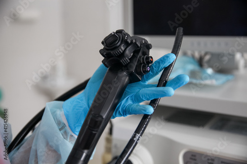 An endoscopist in blue gloves holds an endoscope in his hands. In the frame only the hands with the device are close-up photo