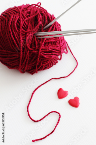 red wool yarn ball with knitting needles and hearts