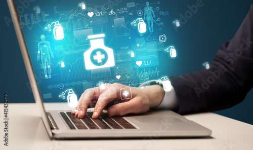 hand browsing on the internet for medical issues with medication icons coming out from the screen