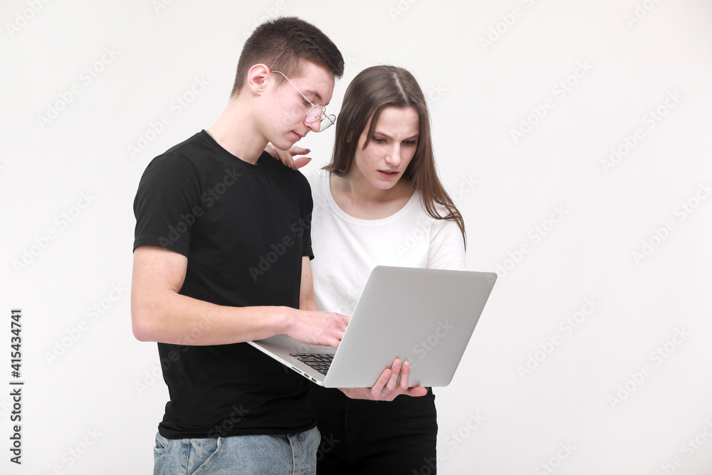Two serious teenager guy and girl are using laptop and discussing something on white background in studio. Male and female surprised Two serious teenager guy and girl are using laptop and discussing something on white background in studio. Male and female surprised
