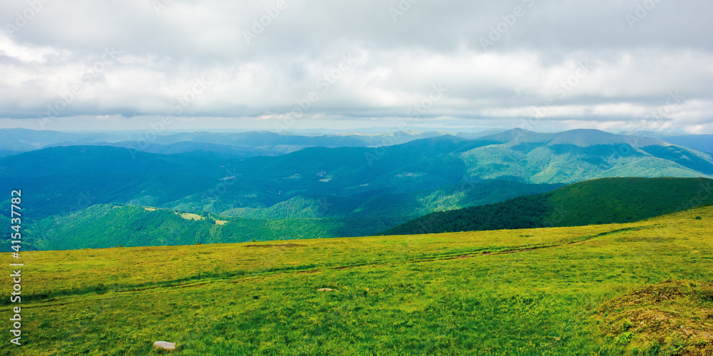 path through mountain meadow. beautiful carpathian landscape in summertime. clouds on the sky above the distant ridge. windy weather