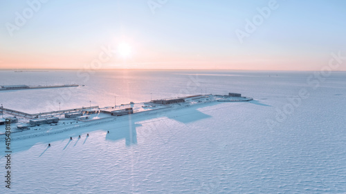Fotografie Frozen sea with empty seaport at sunset