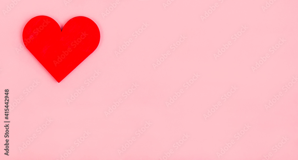 A wooden red heart lies on a pink background. Valentine's Day greeting card. A wooden red heart lies on a pink background. Valentine's Day greeting card.