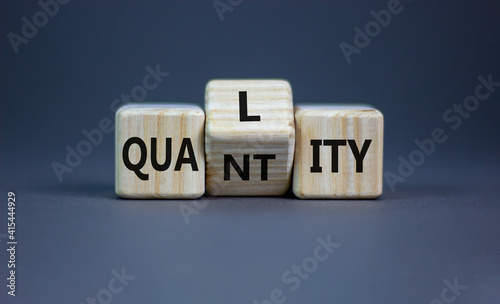 Quality over quantity symbol. Turned cubes and changed the word 'quantity' to 'quality'. Beautiful grey table, grey background, copy space. Business and quality over quantity concept. photo