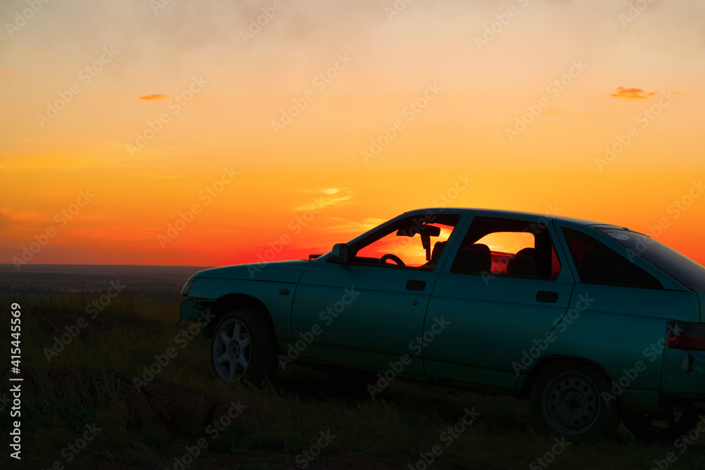 Meeting the sunset from a high slope in the cabin of the car.