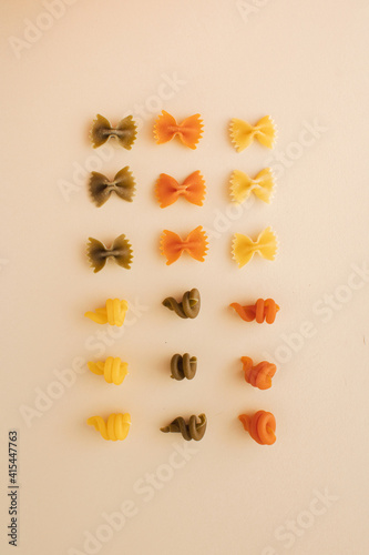 Italian pasta various of shapes and colors, arranged in a square on pastel background. Minimal flat lay concept.