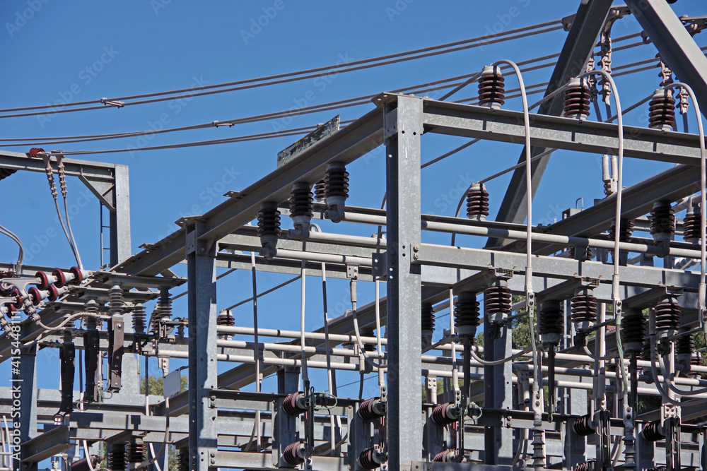 Low angle view of parts of an electricity substation on an ocean bluff under blue sky