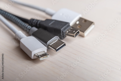 Mini USB, micro USB, and USB type-C connectors, with connecting cables, photographed closely. Evolution and change of USB connectors.