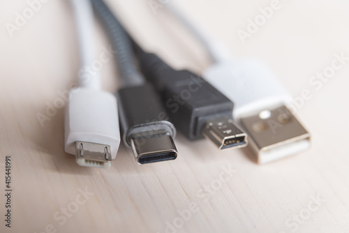 Mini USB, micro USB, and USB type-C connectors, with connecting cables, photographed closely. Evolution and change of USB connectors.